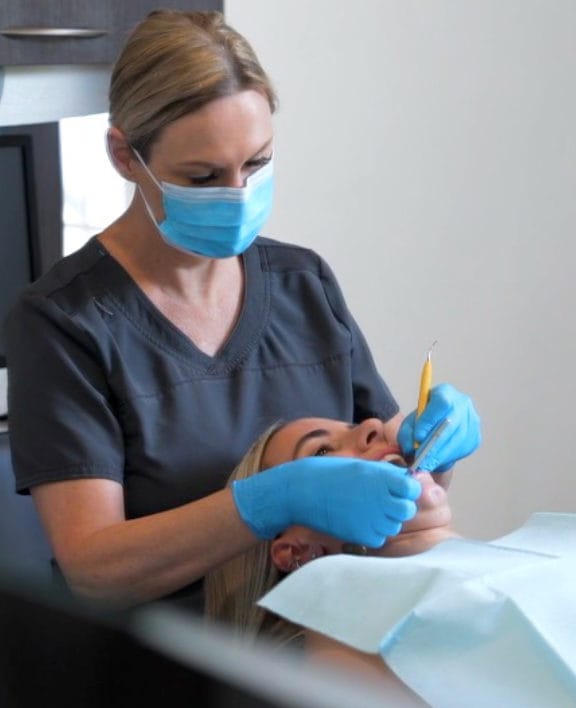 Teen boy sitting in dental chair holding a tooth shaped mirror